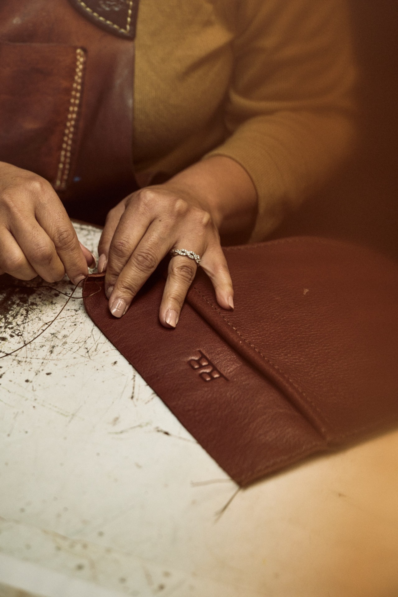 An artisan hand-stitching a Range Revolution leather wallet